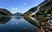 Spegelbilete av Furubergsfossen – Furubergsfossen speglar seg i ein stille fjord i Hardanger, ein vakker sommardag.