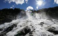 Solglimt på Furubergsfossen – Eit dramatisk bilete av Furubergsfossen med sollys som bryt gjennom vatnet, skapar ei magisk stemning.