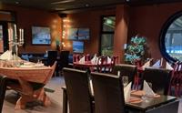 Interiørbilete av restauranten hos Gjøa Sjømat, med ein maritim stil og koselege oppdekka bord klare for gjestar.