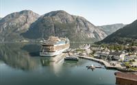 Havneområdet med et cruiseskip, et mindre fartøy, et sjøfly og folk på kaien.