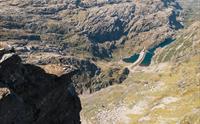 Person står på en massiv fjelltopp og ser utover fjellandskapet.