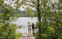 Eit par med eit lite barn ser utover Gullfiskvatnet i Hardanger, omringa av frodig vegetasjon og ein vakker innsjø.