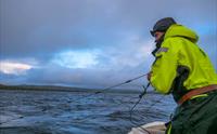 En mann drar inn fiskegarn fra en båt på Hardangervidda.