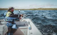 En mann fisker fra båt ved Halnefjorden på Hardangervidda.