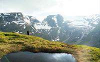 Two men standing beside cairn looking at the fjord and mountain view.