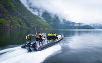 Ribbåt med turistgruppe som nyt ein stille tur gjennom Fyksesund sine majestetiske fjordlandskap.