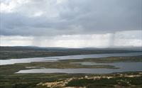 Viser et stort fjellvann under en overskyet himmel.