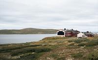 Bilde av Rauhelleren turisthytte, som ligger ved et fjellvann.