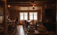 Spisesalen i dunkelt lys. To personer sitter ved vinduet og spiser. Frokostbuffeten vises i forkant.