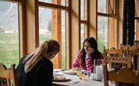 To kvinner spiser fjellørret ved et bord med utsikt.