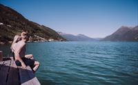 Par sitter på bryggen ved Heit Grimo sauna og nyter solen over Hardangerfjorden.