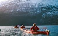 Padlarar kosar seg på fjorden med sol i bakgrunnen