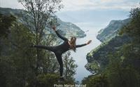 Person balanserer på utsiktspunkt med panorama over Hardangerfjorden, fjell og bygder langs fjorden