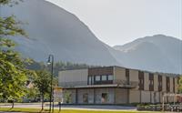 Joker dagligvarebutikk fra utsiden, med høye fjell i bakgrunnen på en solrik dag.