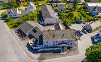 Luftfoto av Jondal Hotel & Gjestgjevarstad, omgitt av grøne hagar og tradisjonelle bygningar i Jondal sentrum, Hardanger.