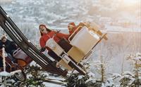Folk som nyter en spennende berg-og-dal-bane-tur i et snødekt vinterlandskap, iført nisseluer og ler av glede.