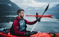 Et par padler kajakk i to røde kajakker på fjorden.