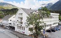 Fasaden til Kinsarvik Fjordhotel med idyllisk utsikt mot Hardangerfjorden, omgitt av vakker natur og fjellandskap.