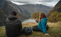 Et par spiser lunsj ved utsiktspunktet Kjeåsen mens de nyter utsikten over fjorden og fjellene.