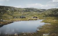 Et lite fjellvann i forgrunnen, Kjeldebu sees i bakgrunnen.