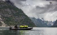 En ribbåt på fjorden, fylt med passasjerer.