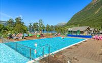 Oppvarma utandørsbasseng på Mikkelparken Ferietun, med spektakulær utsikt over Hardangerfjorden og grøne fjellsider.