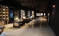 Museumsbutikk med mange varar som står stilt ut. Ein vegg med reip på sneller og smiprodukt. T-skjorter heng utstilt bakerst i lokalet.