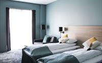 Lyst hotellrom med to enkeltsenger og moderne innreiing.