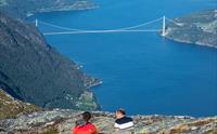 To personar kviler på fjellet med utsikt mot ei fjordbru i Hardanger.