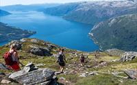 Gruppe turgåarar på veg nedover fjellet med blå fjordutsikt.