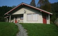 Sjusete Hytter – koseleg tømmerhytte med raude detaljer, omgitt av norsk natur.