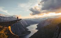 Et kjærestepar står på Trolltunga og ser utover Ringeldasvatnet.
