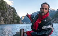 Lokal guide peikar ut naturskjønne attraksjonar under RIB-safarien i Hardanger.