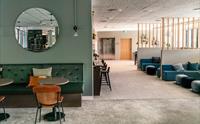 Moderne kaféområde med grøne møblar og ein rund spegel på veggen.