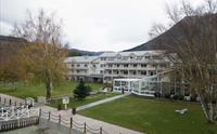 Rosendal Fjordhotel omgitt av grøne hagar og majestetiske fjell.
