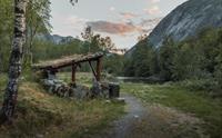 En gapahuk ved elven i solnedgang.
