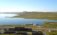 Halne fjellstugu sett fra utsiden, med Halnefjorden i bakgrunnen.