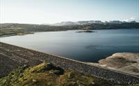 Et dronebilde av Sysendammen-demningen under solnedgang.