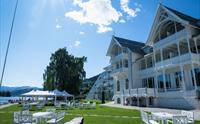 Uteserveringen til Sjøhuset Restaurant og Pub ved Thon Hotel i Norheimsund, med utsikt over Hardangerfjorden og de omliggende fjellene på en solrik dag.