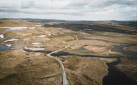 Et dronebilde av Tinnhølvegen, med en skyet himmel i bakgrunnen.