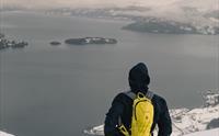 En person på trugetur i vinterlandskap med utsikt til Hardangerfjorden.