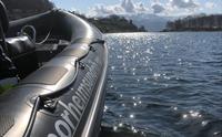 Solglitrande fjordlandskap speglar seg i ein RIB-båt frå Norheimsund RIB Seafari.
