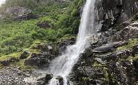 Majestetisk fossefall omgitt av frodig natur i Hardangerfjorden, ein attraksjon på Norheimsund RIB Seafari.
