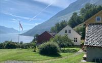 Sjarmerande tun på Jaastad Gjestetun med utsyn til Hardangerfjorden og majestetiske fjell.