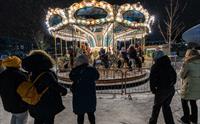 Barn på en karuselltur under et vintermarked, folk står spredt rundt karusellen og ser på barna sine.