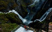 Et dronebilde der du ser tre personer på utsiktsplattformen over fossen.