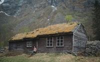 En kvinne sitter på trappen til et av husene på Måbø museum.