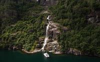 Pilagutt ligg framfor ein mektig foss i Hardangerfjorden – ein magisk stad for naturopplevingar på fjorden.