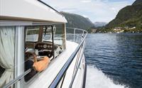 Kapteinen på Pilagutt nyt utsikta medan båten siglar gjennom Hardangerfjorden – ei avslappande og vakker reise.