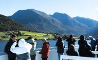 Turistar på dekk på Hardangerfjordekspressen som nyt utsikta av fjord og fjell i Hardanger.
